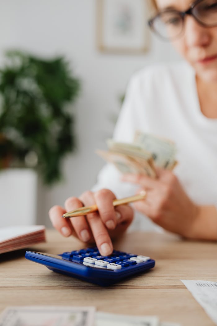 about-03 A woman uses a calculator and holds money, illustrating personal finance management.